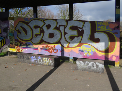 833344 Afbeelding van graffiti met de tekst 'DEBIEL', op een wand van de voetbalkooi in het Griftpark te Utrecht.